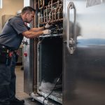 Technician inspecting a walk-in cooler condenser during a San Diego repair visit